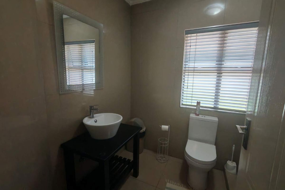 A functional bathroom featuring a modern vessel sink vanity, a standard toilet, and neutral wall tiling with a window for natural light.