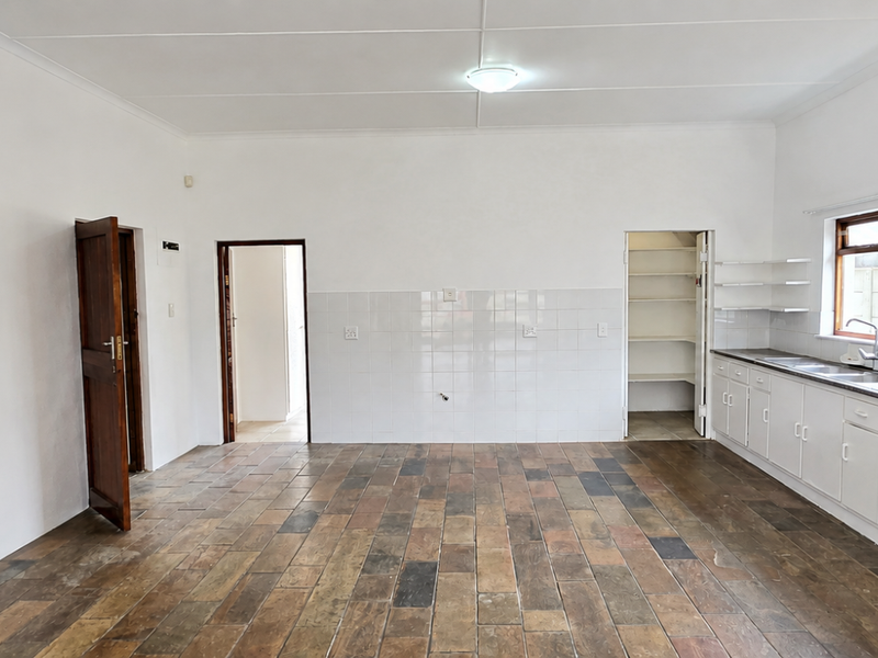 Spacious kitchen featuring tiled flooring, ample built-in cabinetry, a stainless steel sink, and a convenient walk-in pantry area.