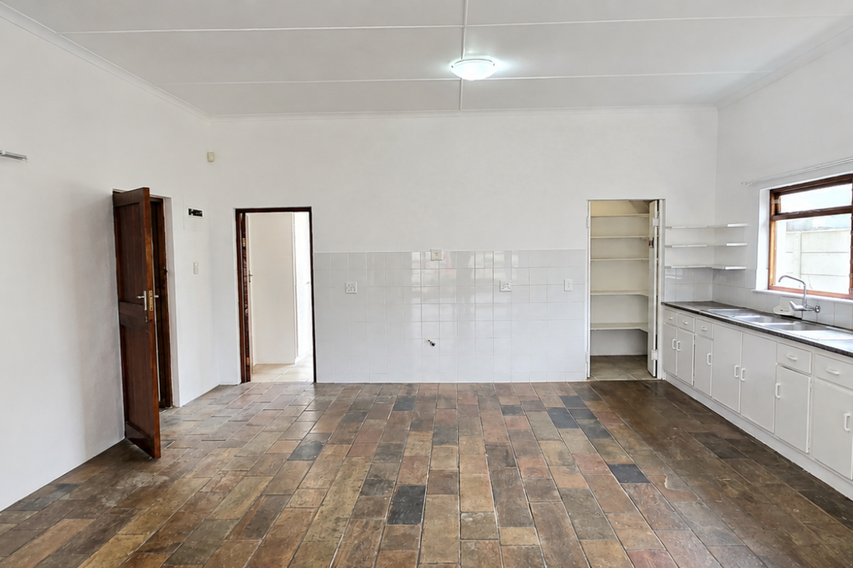 Spacious kitchen featuring tiled flooring, ample built-in cabinetry, a stainless steel sink, and a convenient walk-in pantry area.