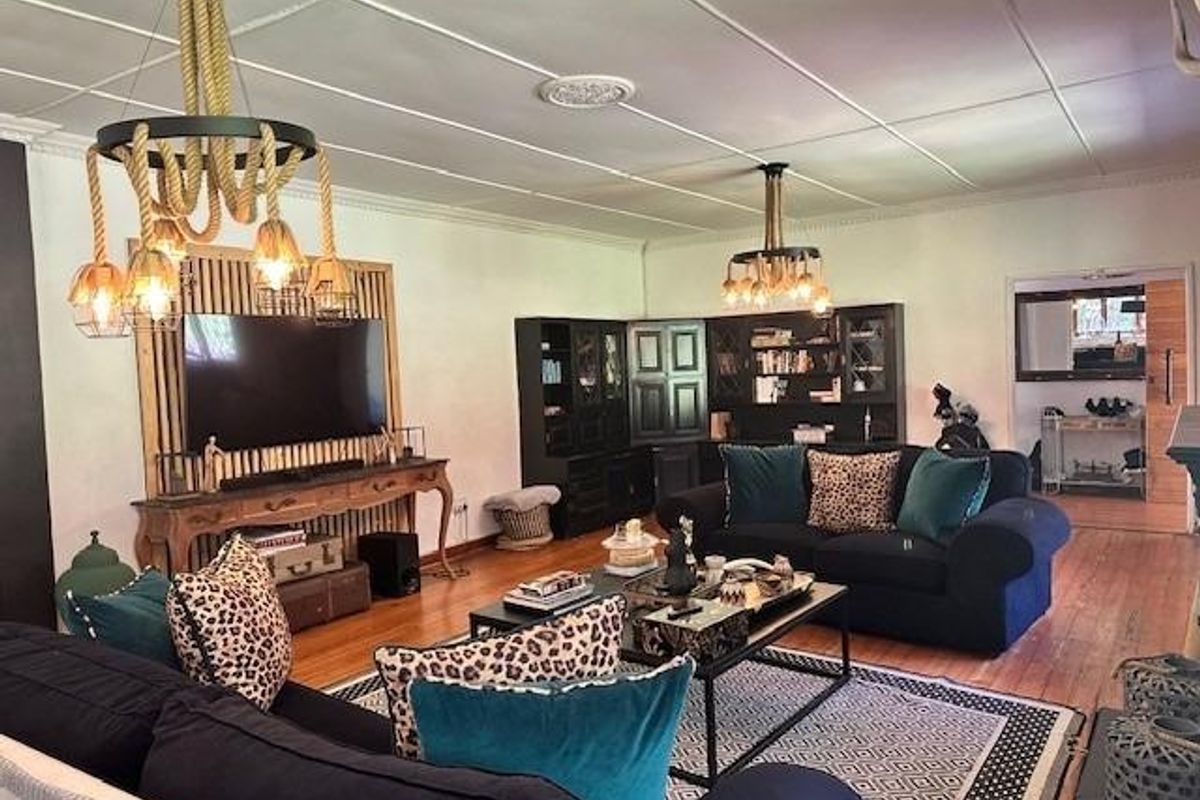 Spacious living room featuring hardwood flooring, decorative ceiling panels, and custom built-in cabinetry, complemented by unique rope pendant lighting fixtures.