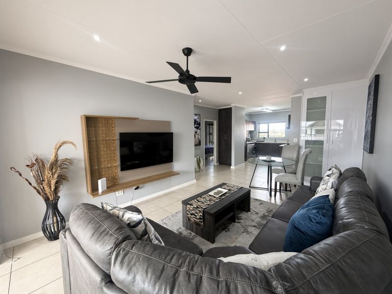 Spacious open-plan living area featuring tiled floors, recessed lighting, a ceiling fan, and a modern kitchen with built-in cabinetry.