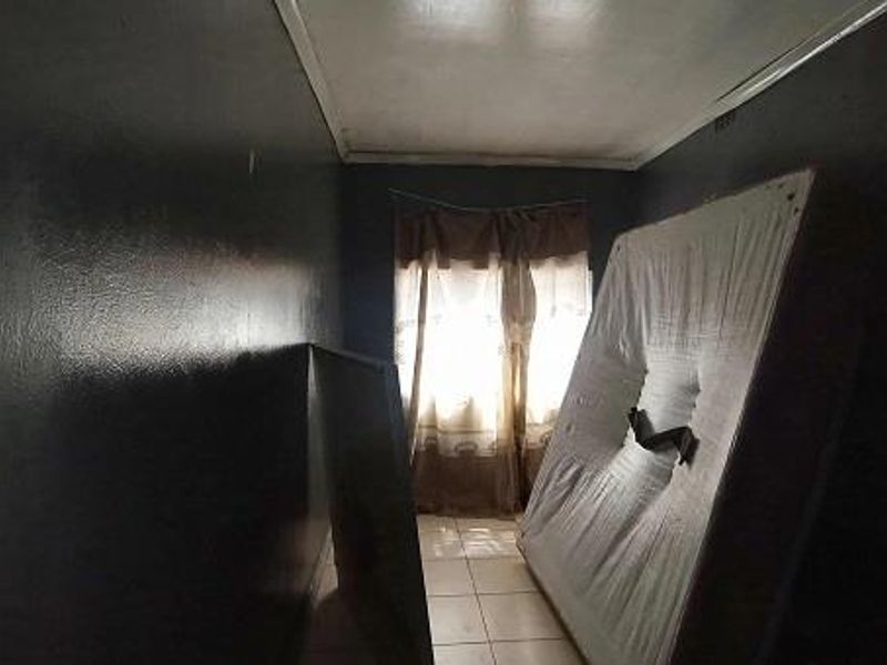 A vacant bedroom featuring tiled flooring and dark-painted walls, offering a blank canvas for renovation or restyling.