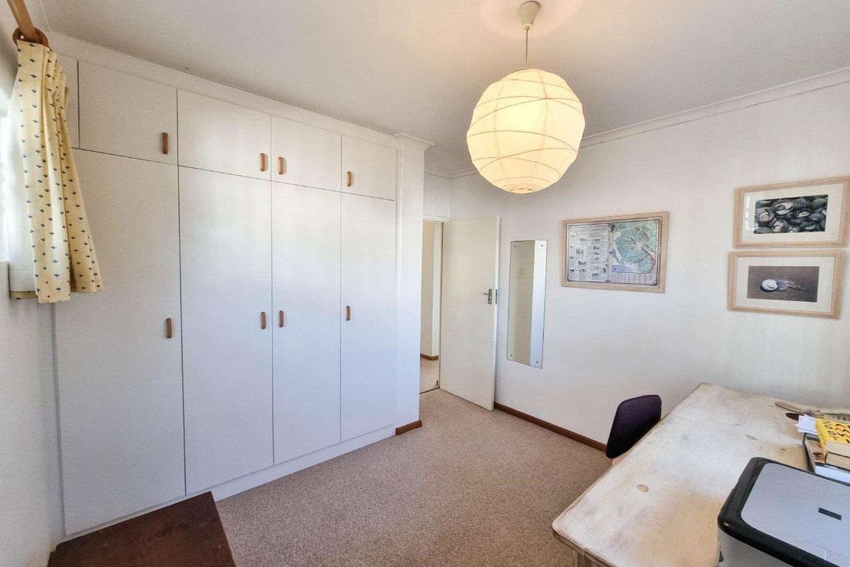 A bedroom featuring built-in floor-to-ceiling cabinetry, neutral carpeting, and a standard door leading to the hallway.