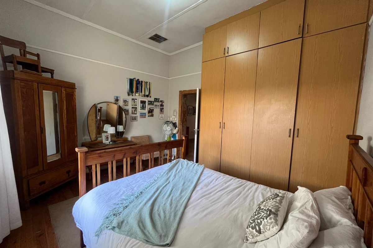 A bedroom featuring built-in wooden cupboards and traditional high ceilings, offering a functional and classic living space.