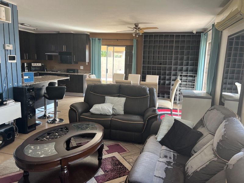 Open-plan living and dining area featuring a modern kitchen with granite countertops, breakfast bar, and integrated cabinetry, flowing into a spacious lounge.