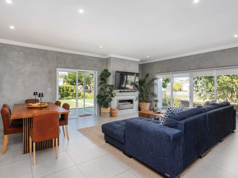 Spacious open-plan living and dining area featuring modern tiled floors, recessed lighting, a built-in fireplace, and large sliding doors opening to the garden.