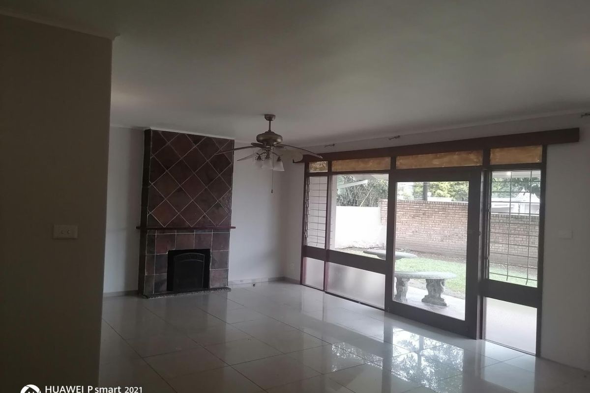 Spacious living room featuring tiled flooring, a built-in tiled fireplace, and large glass sliding doors providing access to the rear garden area.