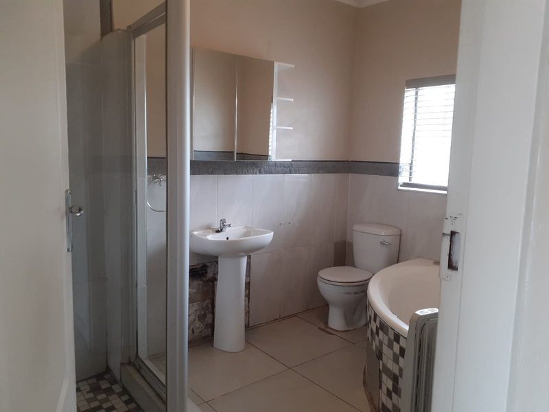 A functional bathroom featuring a pedestal basin, shower enclosure, toilet, and built-in bathtub, requiring cosmetic attention to wall finishes and fixtures.