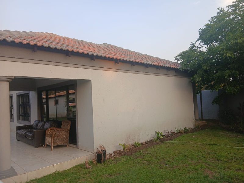 Rear view of the property featuring a covered patio area with tiled flooring, sliding glass doors, and a tiled roof structure.