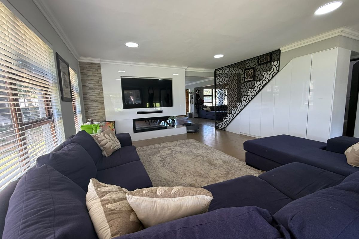 Spacious living room featuring a modern built-in fireplace, decorative metal staircase screen, and extensive built-in storage cabinetry with recessed lighting.