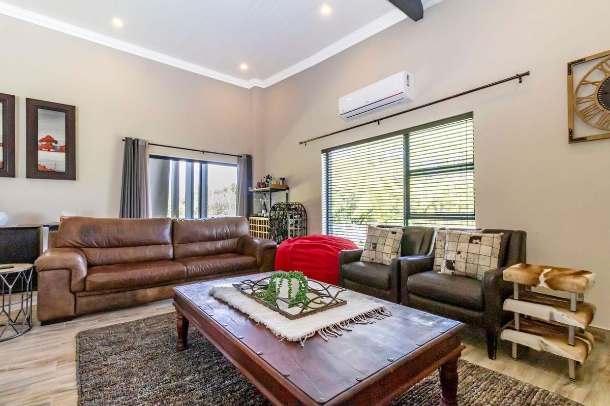 A spacious living room featuring high ceilings, tiled flooring, and a wall-mounted air conditioning unit, providing a comfortable and well-maintained living space.