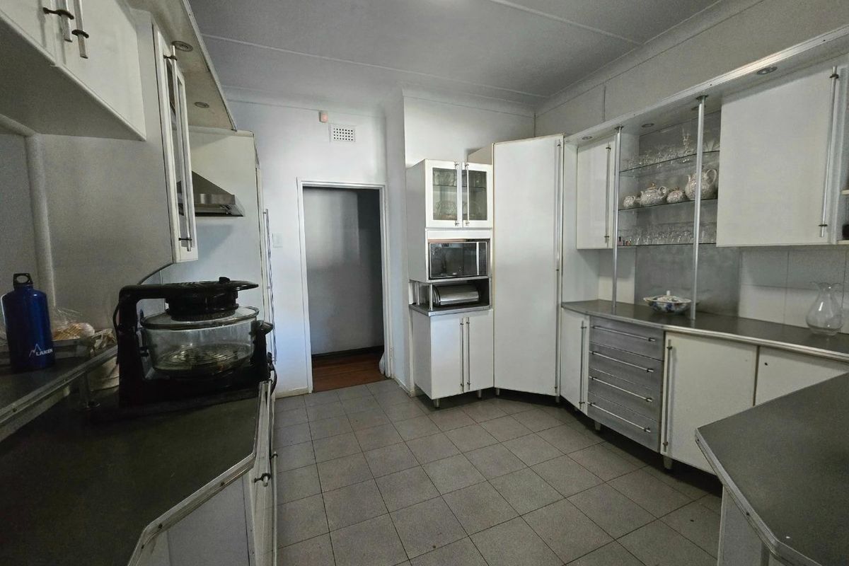 A functional kitchen featuring white built-in cabinetry, laminate countertops, integrated microwave, extractor fan, and tiled flooring.
