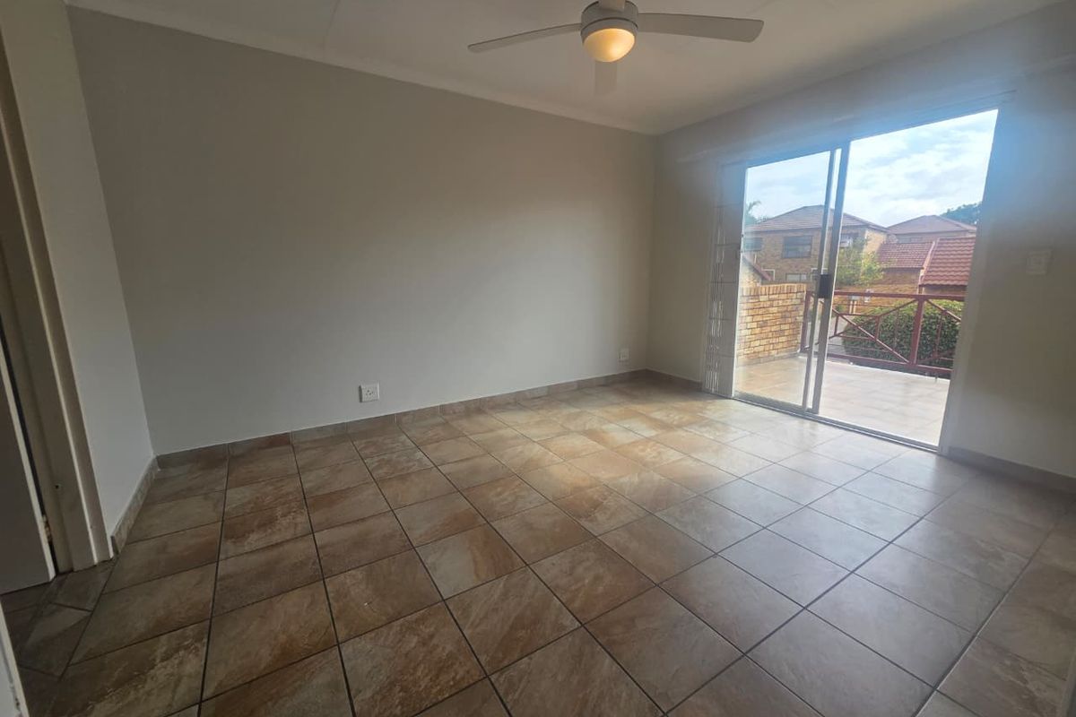 An empty bedroom featuring tiled flooring, a ceiling fan, and a sliding glass door providing access to an outdoor balcony area.