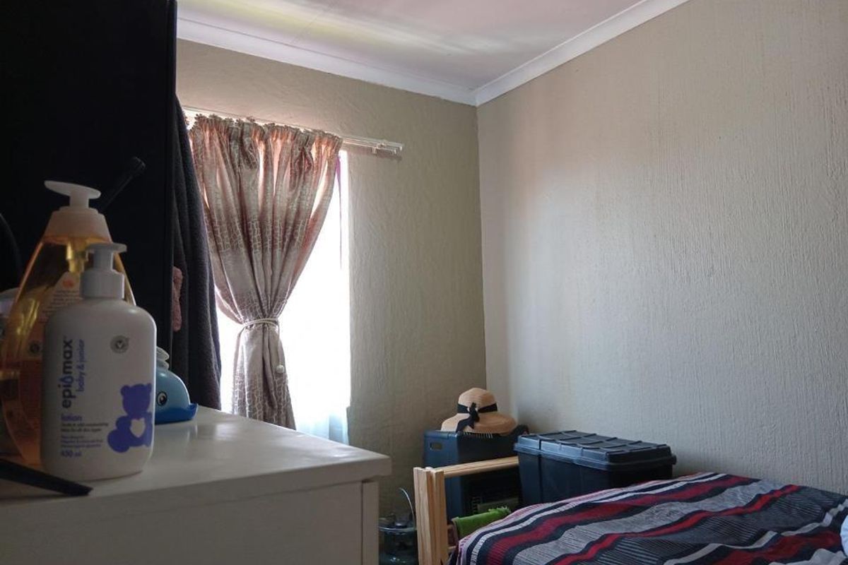 A bedroom featuring neutral wall paint, coved ceiling cornices, and a window with curtain tracks.