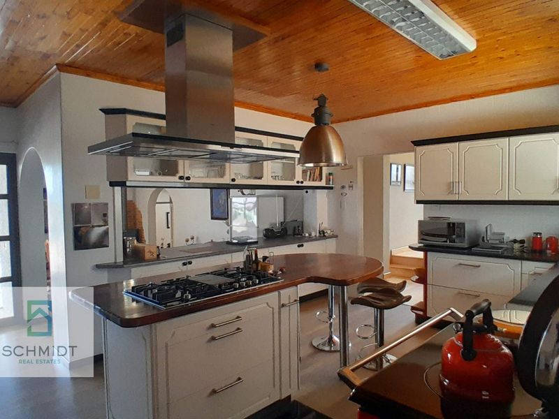 Spacious kitchen featuring a central island with a gas cooktop, stainless steel extractor fan, timber ceiling, and ample built-in cabinetry.