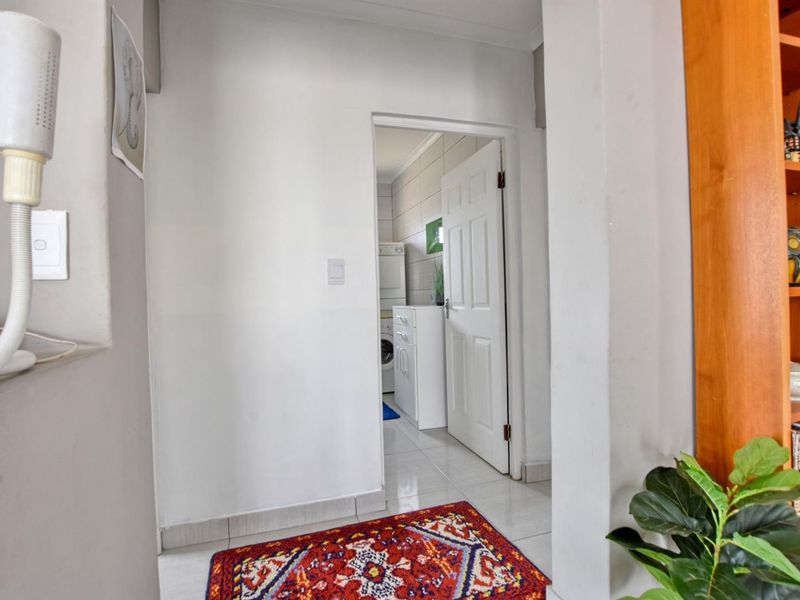 A bright hallway featuring tiled flooring and built-in shelving, providing a clear view into the adjacent laundry area.