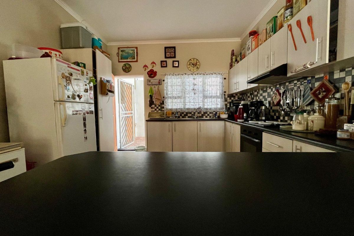 A functional kitchen featuring built-in cabinetry, a dark countertop, a tiled backsplash, and an integrated extractor fan with direct access to the exterior.