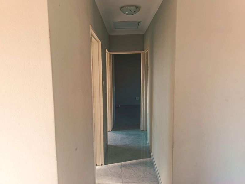 A functional, empty hallway featuring neutral tiled flooring and access to multiple rooms, providing a clean canvas for interior updates.
