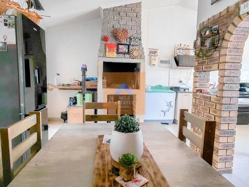 Open-plan living and kitchen area featuring a prominent brick fireplace with a built-in braai and a decorative brick archway.