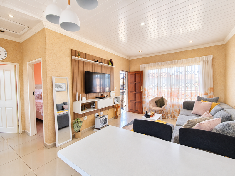 Bright open-plan living area featuring tiled floors, a tongue and groove ceiling with recessed lighting, and a custom built-in media wall unit.
