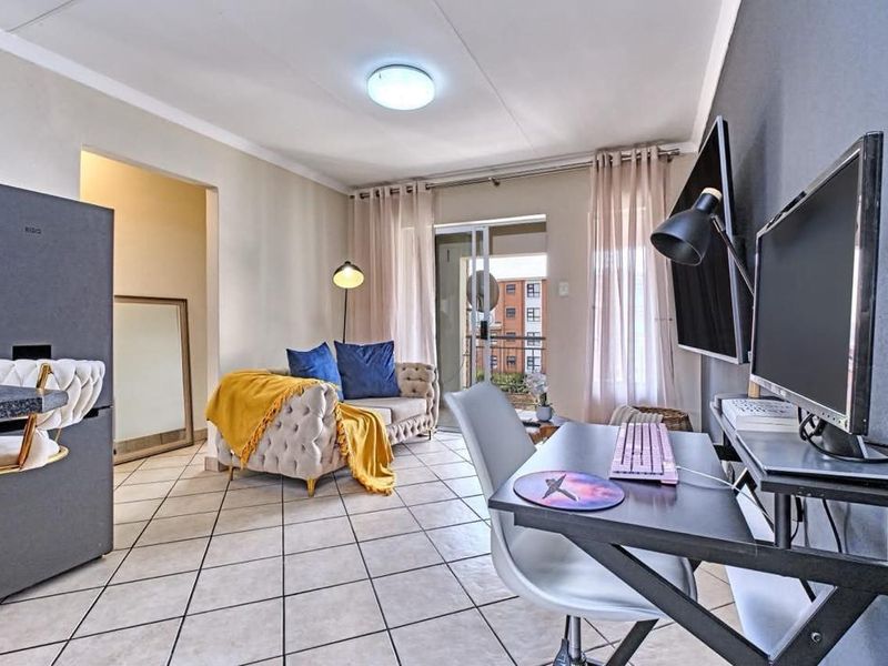 Open-plan living area featuring tiled flooring, neutral walls, and a sliding glass door leading to a balcony.