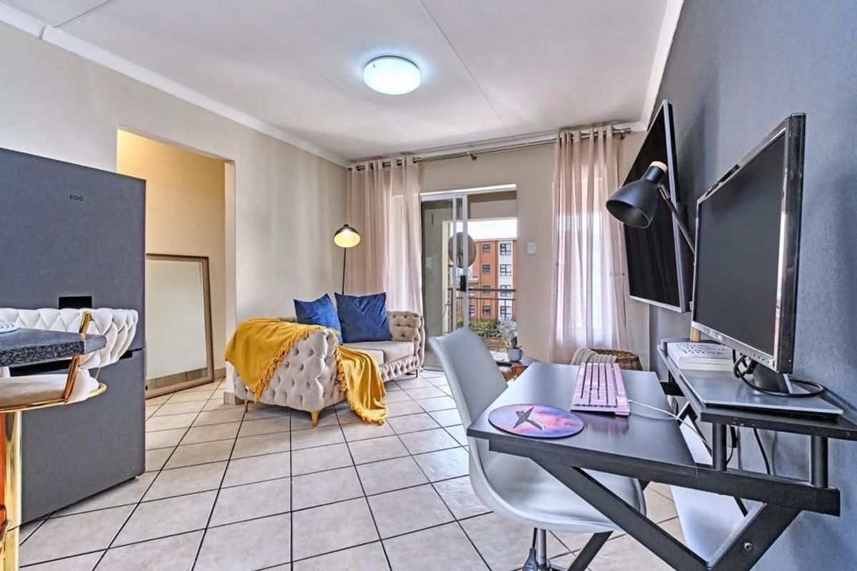Open-plan living area featuring tiled flooring, neutral walls, and a sliding glass door leading to a balcony.