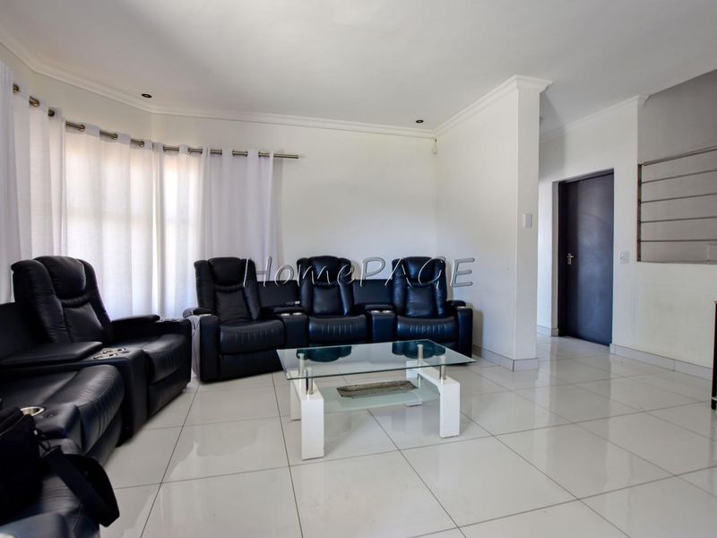 A bright living room featuring large format floor tiles, recessed lighting, and coved cornicing, providing a clean and neutral foundation for interior design.