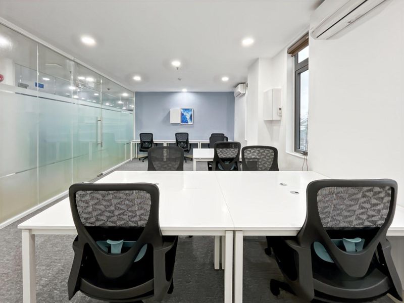 A modern, well-lit office space featuring glass partitions, carpeted flooring, and integrated air conditioning, providing a professional and functional work environment.
