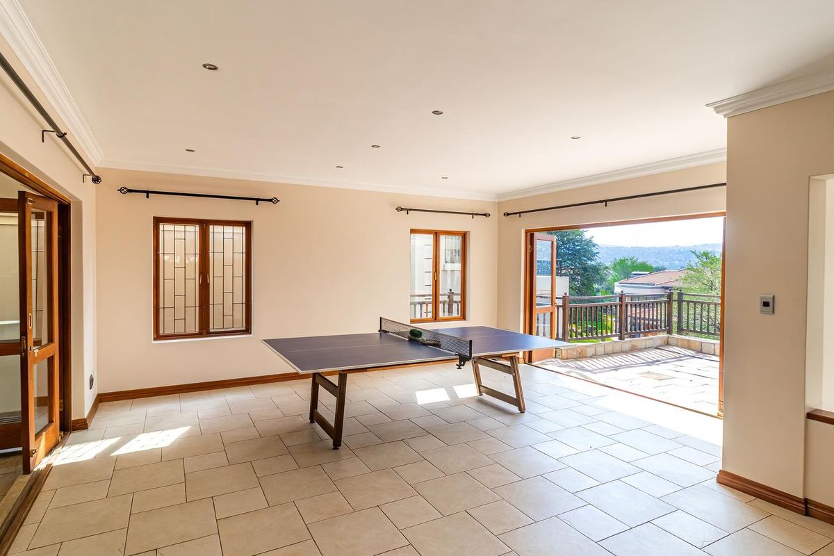 Spacious living area featuring tiled flooring, recessed lighting, and large wooden doors opening onto a balcony with scenic views.