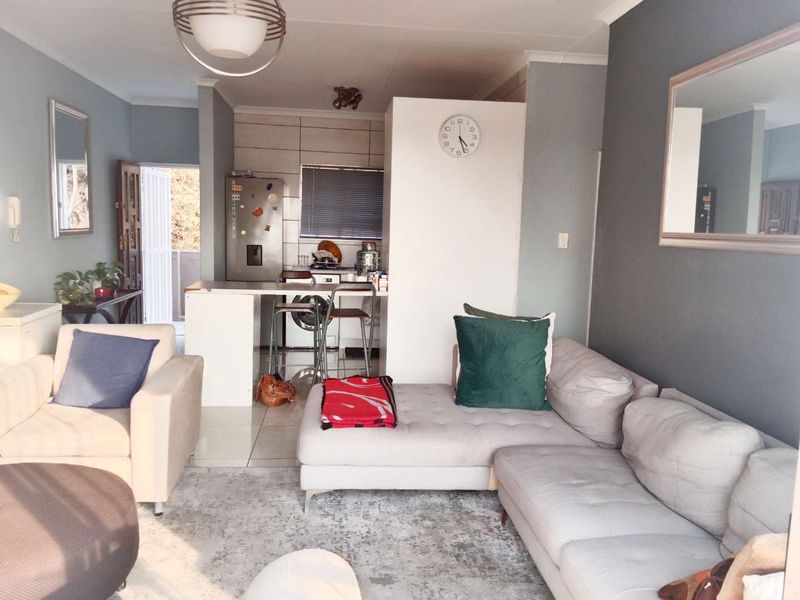 An open-plan living area featuring a compact kitchen with a breakfast island, tiled flooring, and neutral wall tones, creating a functional living space.