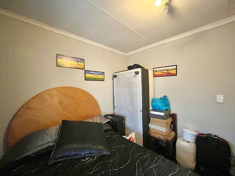 A bedroom featuring standard wall finishes and ceiling cornice, currently showing signs of wear and requiring cosmetic updates.