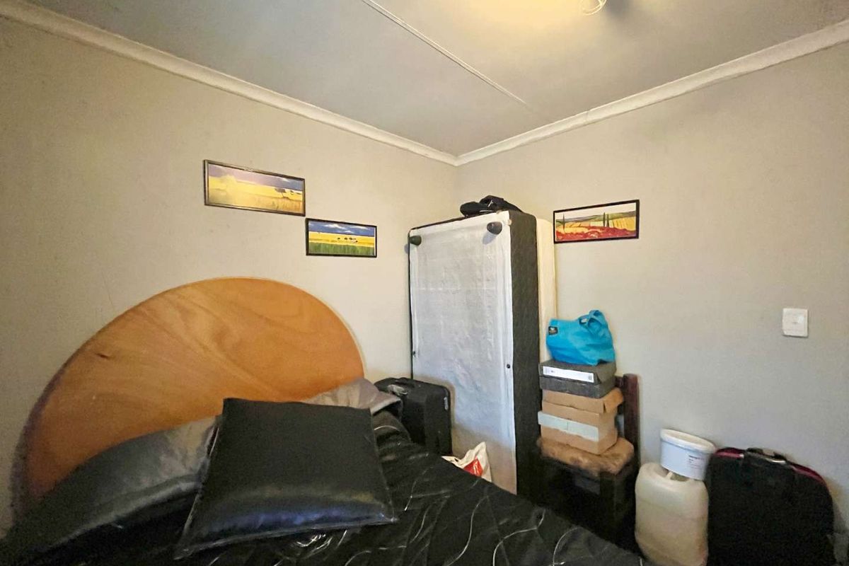 A bedroom featuring standard wall finishes and ceiling cornice, currently showing signs of wear and requiring cosmetic updates.