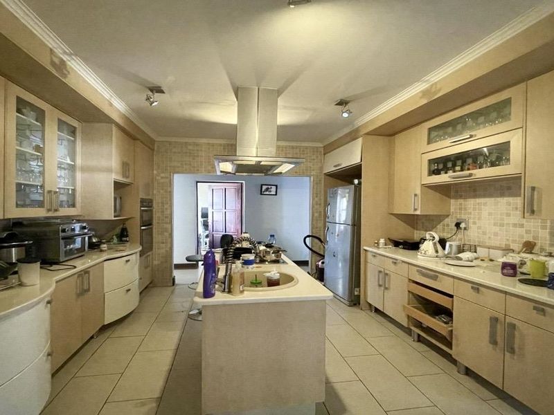 Spacious kitchen featuring a central island, stainless steel extractor fan, built-in oven, and ample cabinetry with a mosaic tile backsplash.