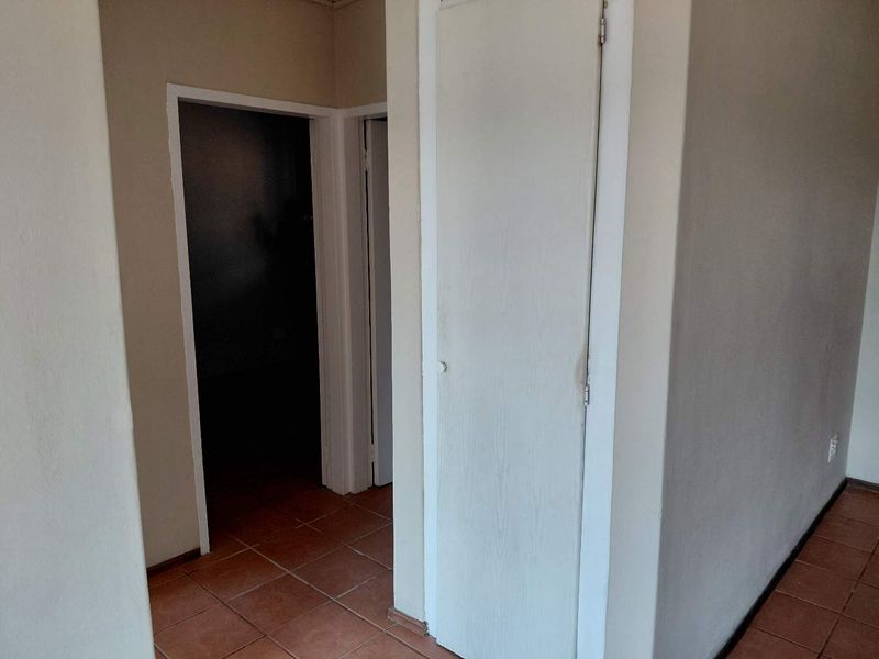 A functional hallway featuring tiled flooring and a built-in storage cupboard, providing access to adjacent rooms within the townhouse.