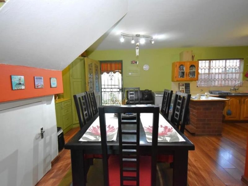 Open-plan dining and kitchen area featuring laminate flooring, brick kitchen island, and direct access to the exterior via a security gate.