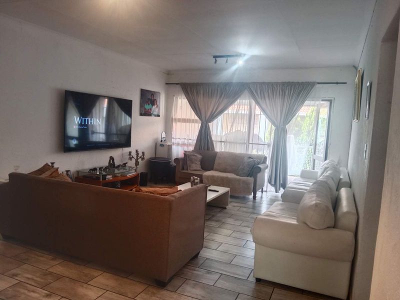 A spacious living room featuring tiled flooring and a sliding glass door that provides access to the exterior, offering natural light and ventilation.