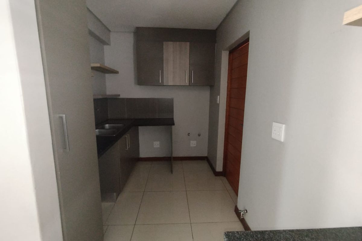 A clean, modern kitchen featuring built-in cabinetry, laminate countertops, and tiled flooring, offering a functional and well-maintained space.