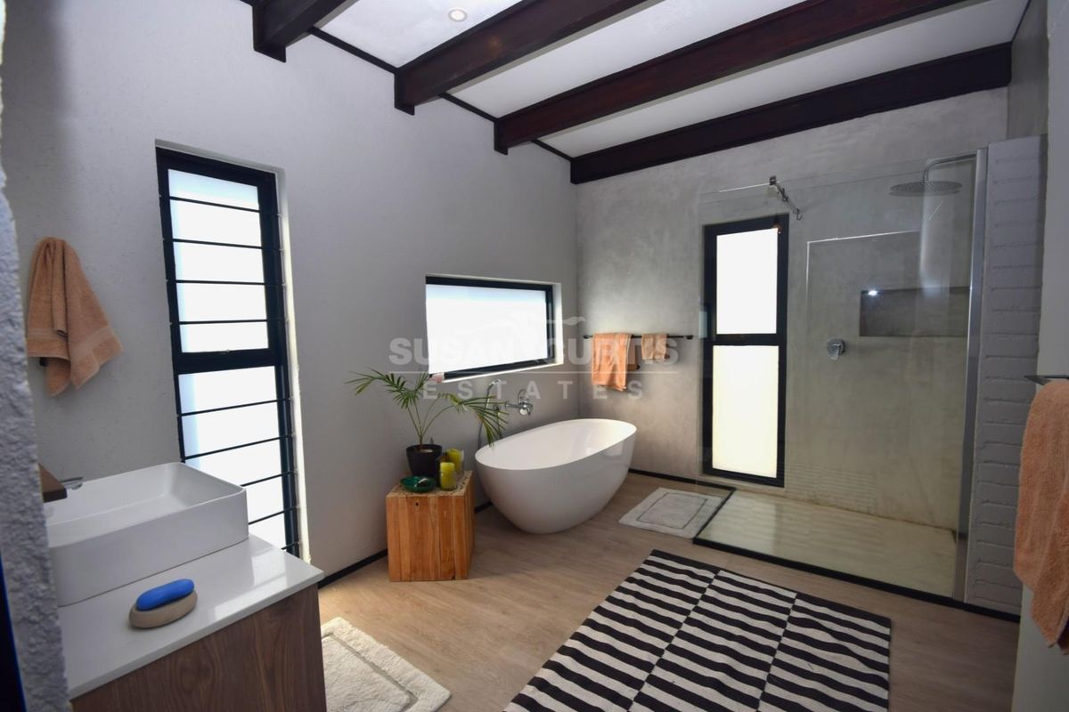 Modern bathroom featuring a freestanding bathtub, walk-in shower with glass enclosure, exposed timber ceiling beams, and a contemporary vanity with a vessel sink.