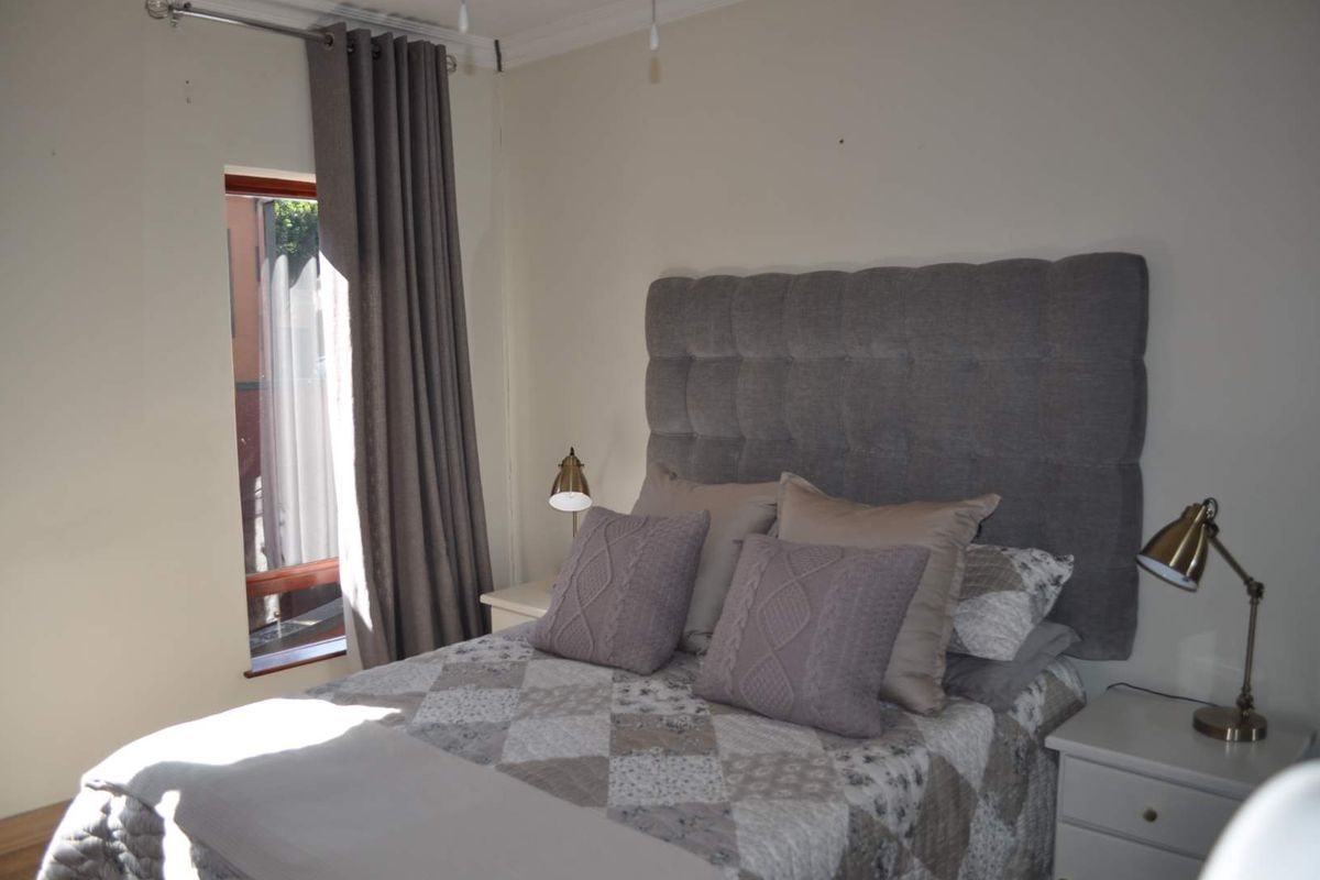 A neutrally decorated bedroom featuring a window with curtain tracks and ceiling cornicing.
