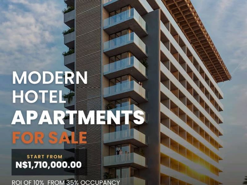 A modern multi-story hotel apartment building featuring contemporary architectural design with glass balconies and a prominent overhanging roof structure.