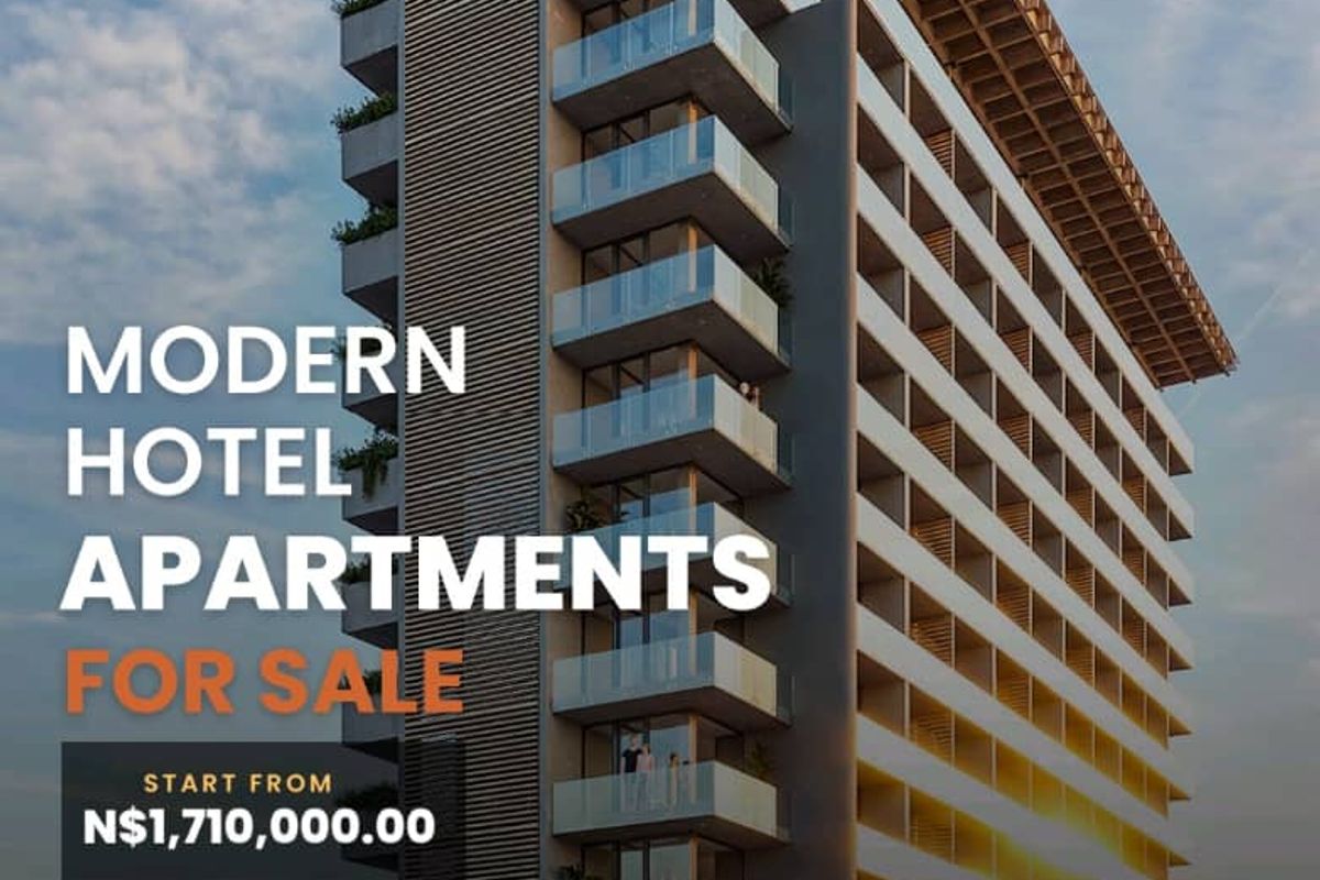 A modern multi-story hotel apartment building featuring contemporary architectural design with glass balconies and a prominent overhanging roof structure.