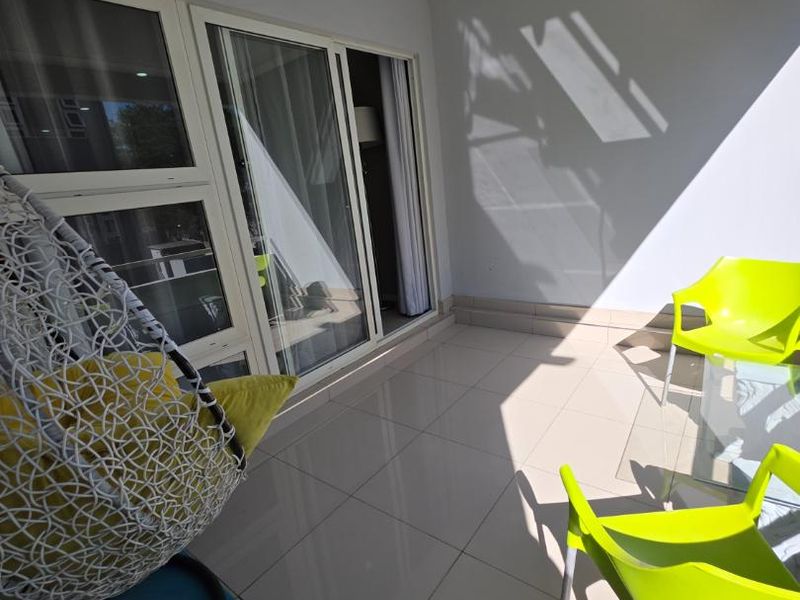 A clean, tiled balcony featuring large sliding glass doors that provide seamless access to the interior living space.