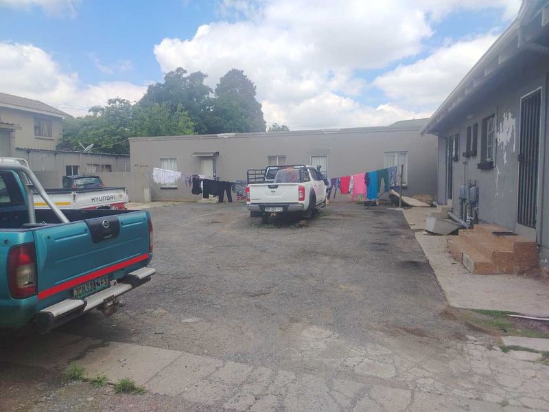 Rear exterior view of the property featuring an asphalt driveway, concrete steps, and building facade with visible paint wear.