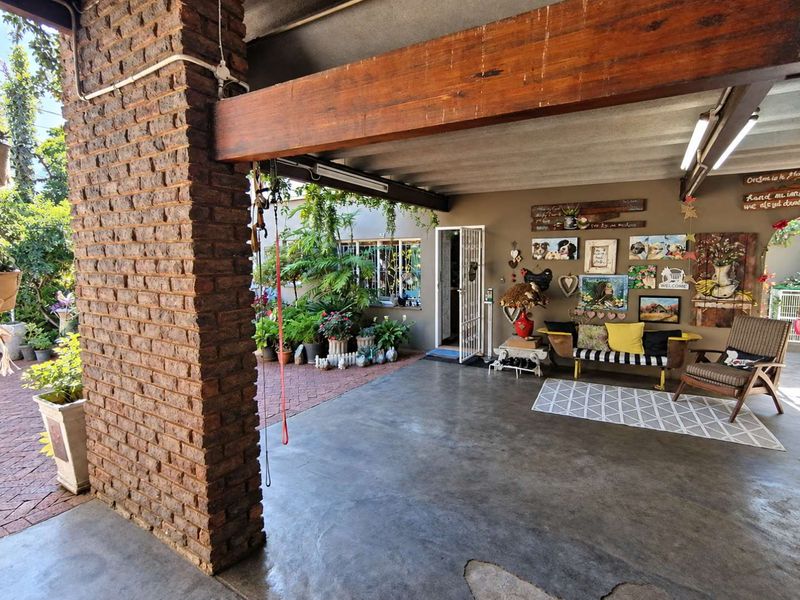 A covered outdoor patio area featuring exposed brickwork, timber beams, and concrete flooring, providing a versatile space for outdoor living.