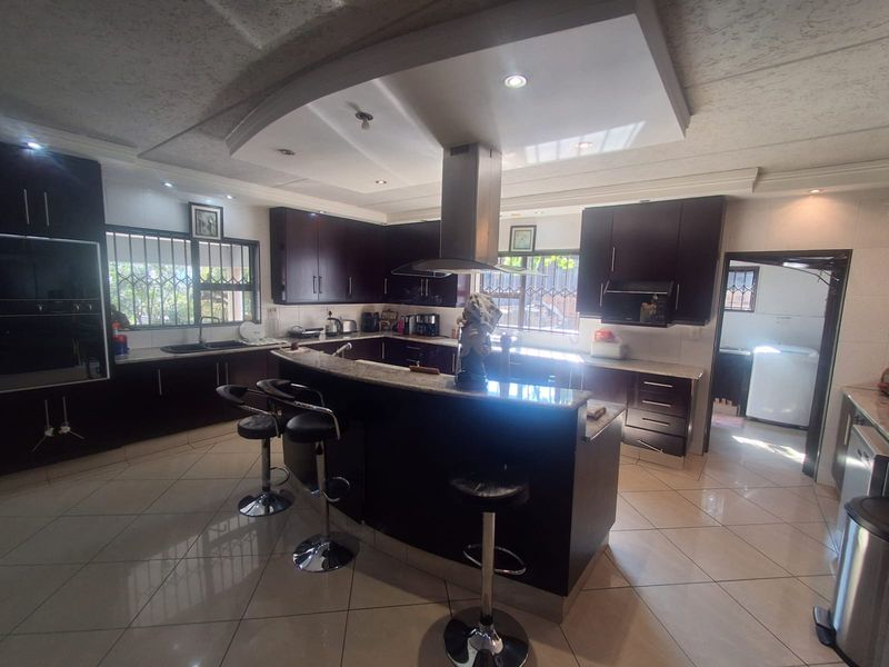 Spacious kitchen featuring dark wood cabinetry, granite countertops, a central island with breakfast bar, and integrated stainless steel appliances.