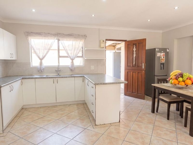 A functional kitchen featuring white cabinetry, laminate countertops, tiled flooring, and recessed lighting, offering a clean and practical workspace.