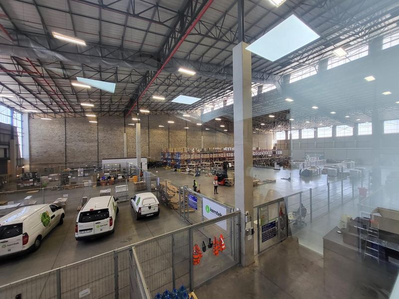 Spacious industrial warehouse facility featuring high ceilings, exposed steel trusses, concrete flooring, and integrated office partitioning.
