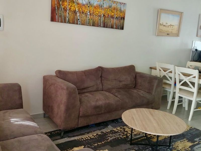 A well-maintained living room featuring neutral wall tones, tiled flooring, and decorative coving, providing a comfortable and functional space.