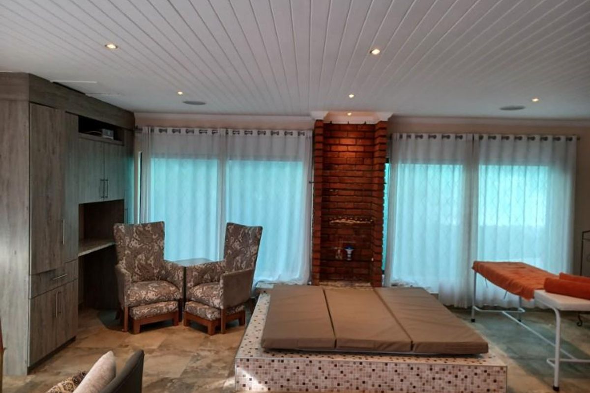 Spacious living area featuring a built-in brick fireplace, tiled flooring, recessed ceiling lighting, and integrated cabinetry.