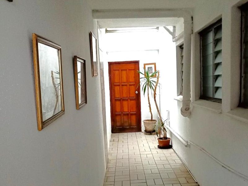A functional hallway featuring tiled flooring, louvre windows, and a solid timber door, providing a clean and simple transition space within the apartment.